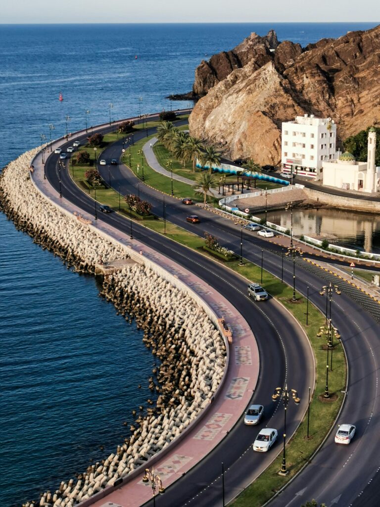 pexels-photo-16460677-16460677 Aerial view of Muscat's stunning Mutrah Corniche with coastal road and Mutrah Fort, perfect for travel and tourism.